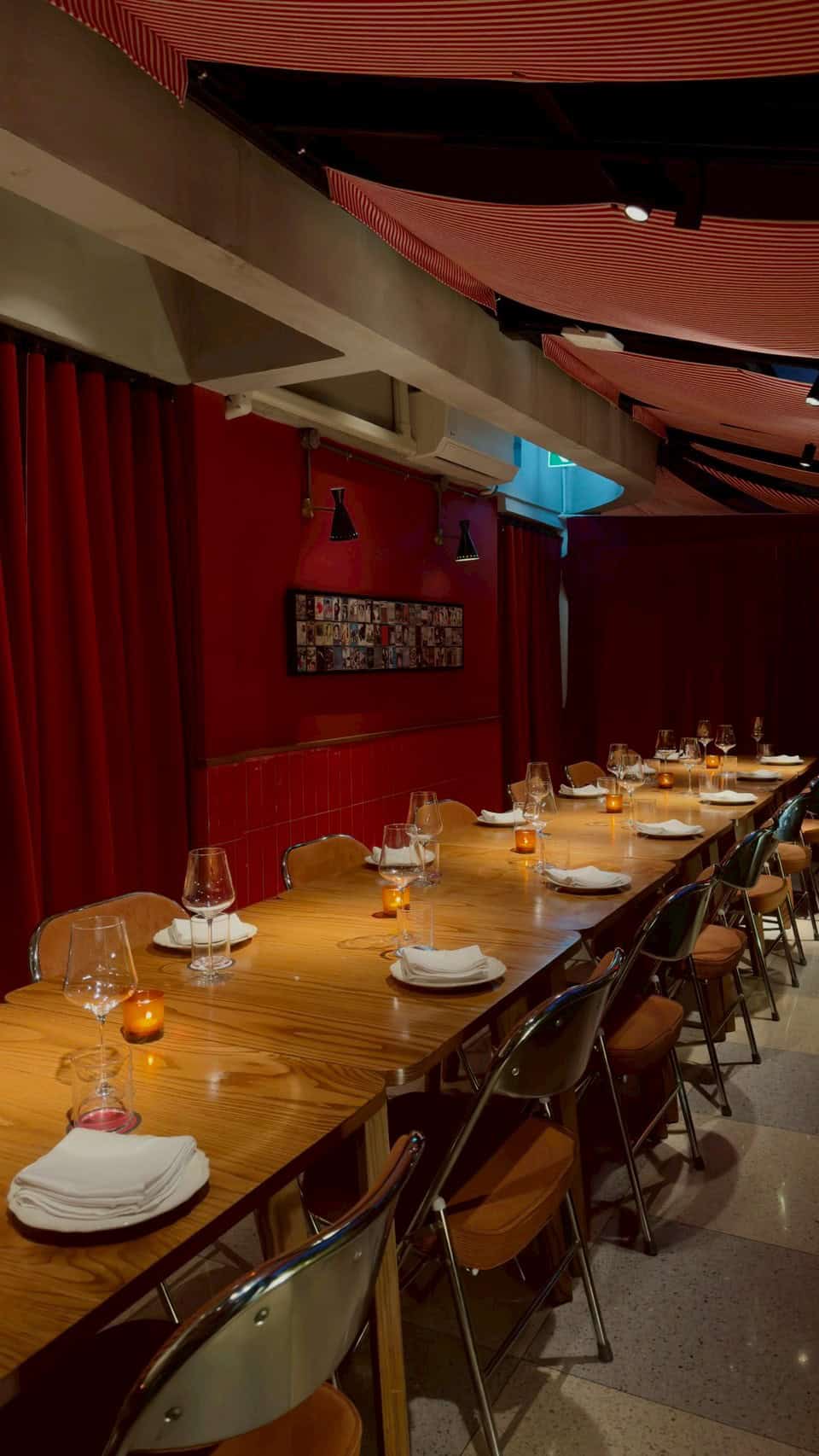 Beautiful dining setup at Capricci Bangkok featuring a long wooden table, wine glasses, and warm ambiance.