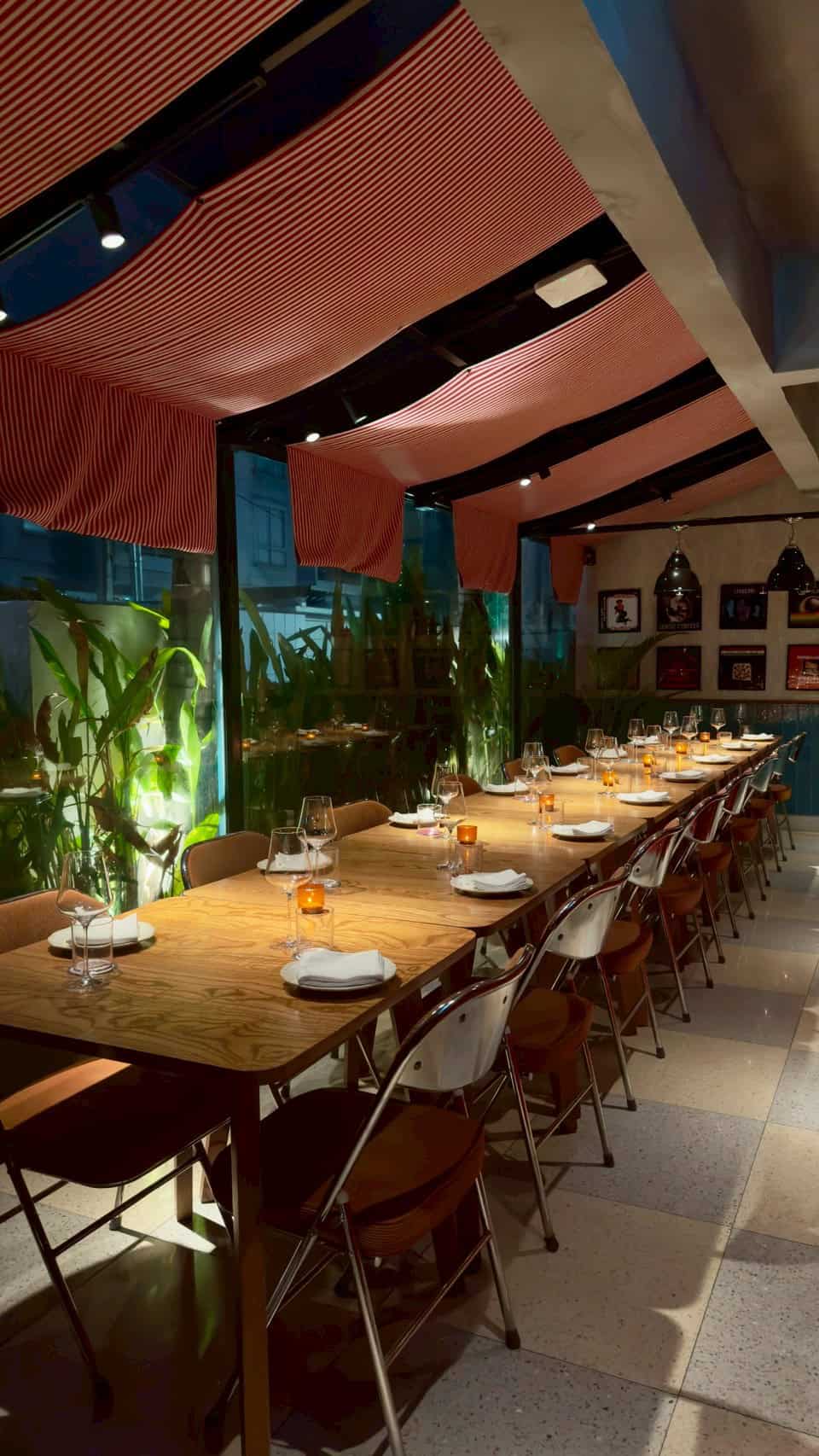 Stylish restaurant interior with wooden table, wine glasses, candles, and modern decor.