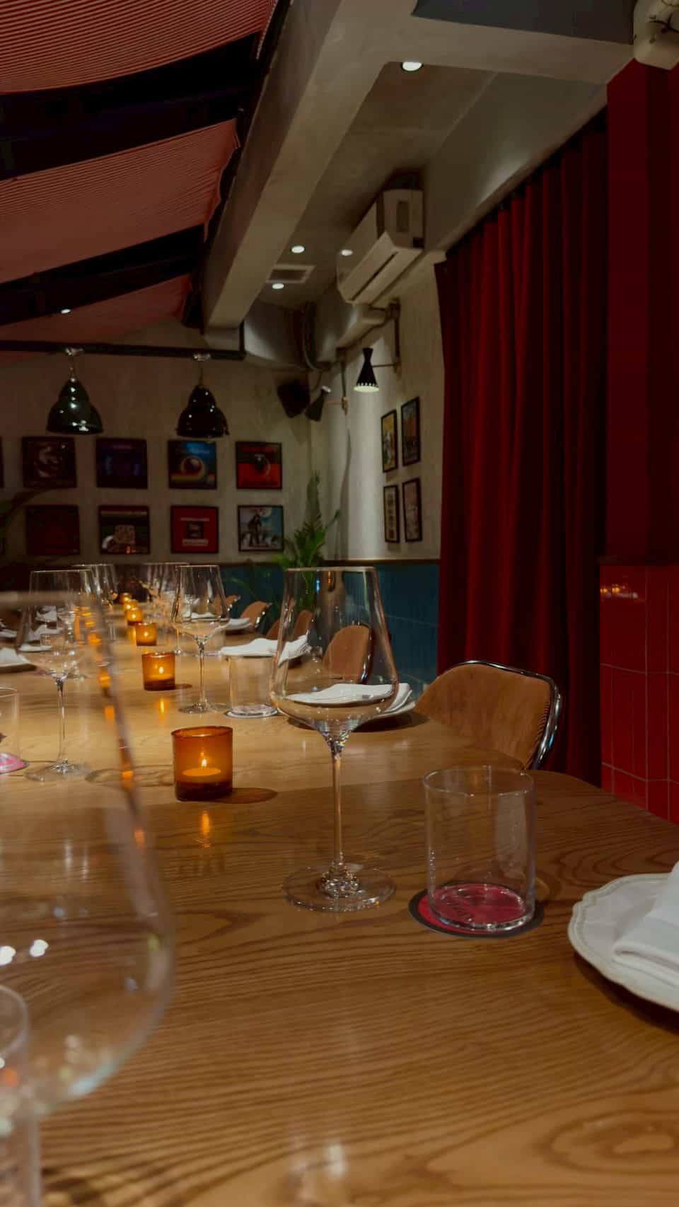 Chic dining area at Capricci Bangkok with wine glasses, candles, and cozy atmosphere.